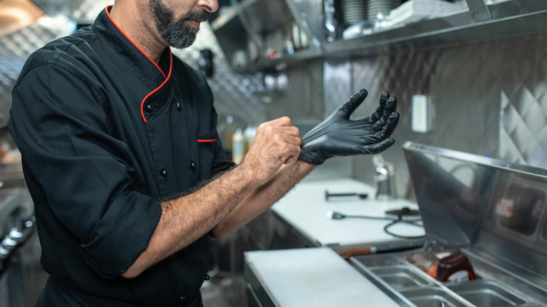 a chef is wearing black nitrile gloves before preparing food