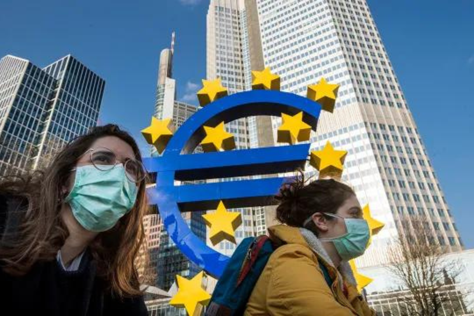 Two ladies wear masks under Euro Sign